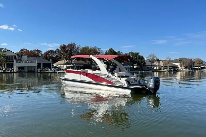 Slide: The Image of 2021 Bennington 25 RXSBA pontoon boat on a calm lake with waterfront homes. - 9
