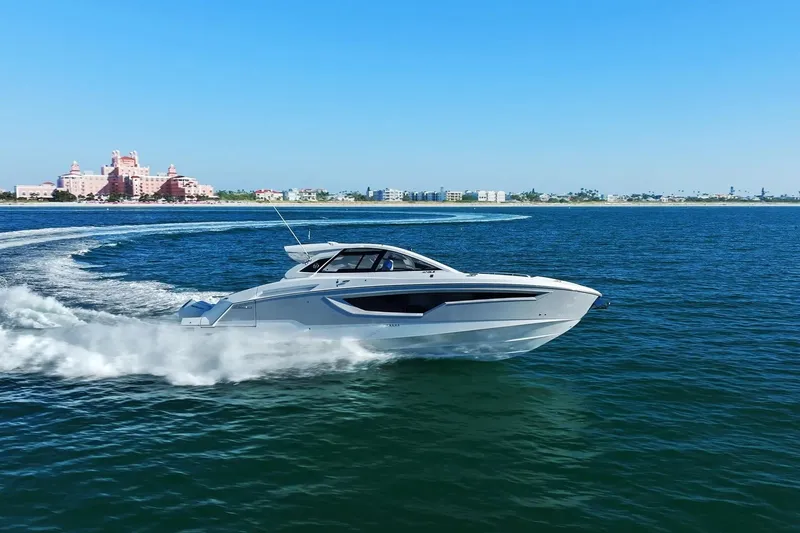 The Image of 2026 Cruisers Yachts 42 GLS OB cruising on open water, with coastal buildings in the background. - 0