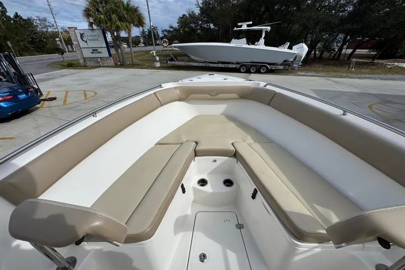 Slide: The Image of 2020 Sailfish 242 CC boat interior with beige seating, parked outdoors. - 19