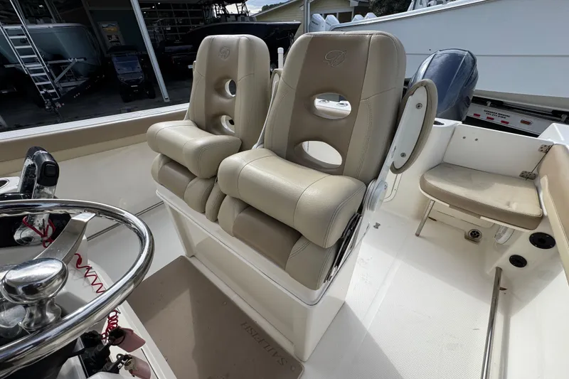 Slide: The Image of 2020 Sailfish 242 CC boat interior with dual beige captain's chairs and steering wheel. - 28