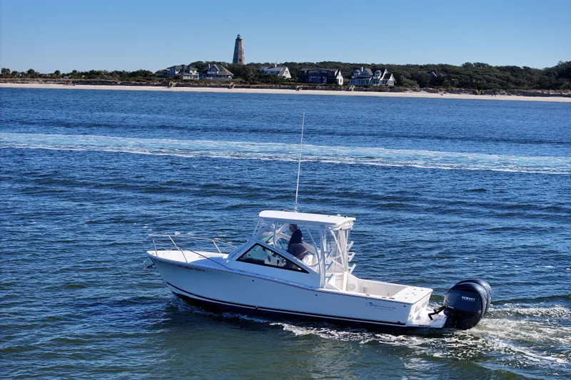 Slide: The Image of 2022 Albemarle 25 Express boat cruising near a scenic coastline with lighthouse. - 44