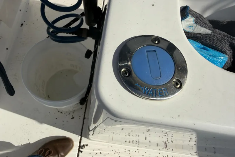Slide: The Image of 2024 Clearwater 2800 boat water fill cap with hose and bucket nearby. - 44