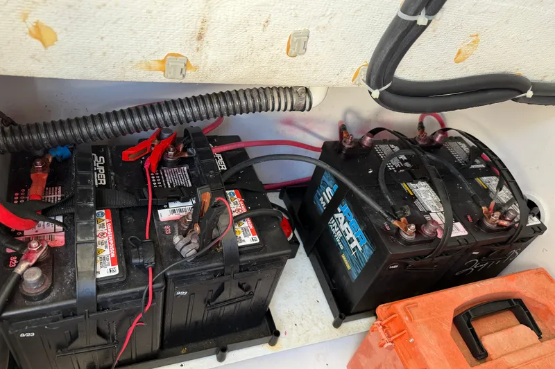 Slide: The Image of Batteries in a 2024 Clearwater 2800 boat, connected with cables and clamps. - 63