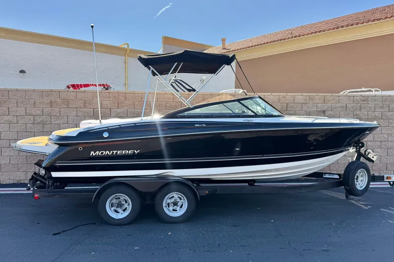 The Image of 2019 Monterey 224FS boat on trailer, black hull, parked outdoors. - 0