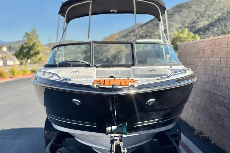 Slide: The Image of 2019 Monterey 224FS boat with black hull, parked outdoors, mountainous background. - 2