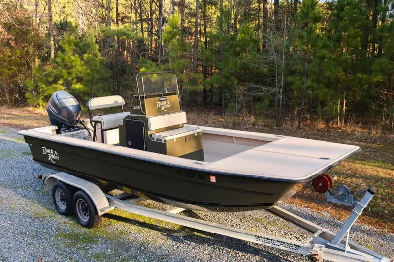 Slide: The Image of 2015 Bay Rider 2060 boat on trailer, parked outdoors near forested area. - 4