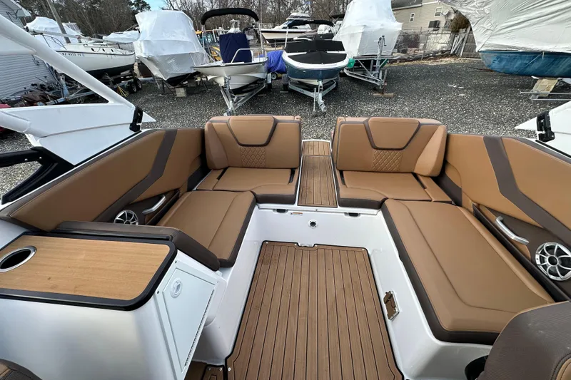 Slide: The Image of 2024 Yamaha Boats 252SE interior with brown seating and wood accents, docked among other boats. - 14