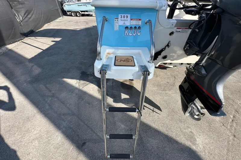 Slide: The Image of 2022 NauticStar 195 XTS boat with ladder and outboard motor, parked on pavement. - 17