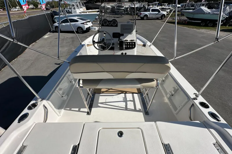 Slide: The Image of 2022 NauticStar 195 XTS boat interior with steering console and seating, parked outdoors. - 22