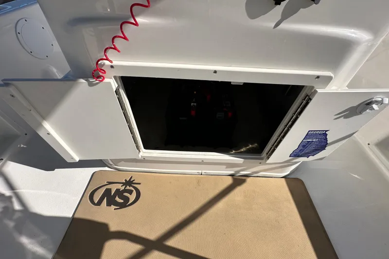 Slide: The Image of 2022 NauticStar 195 XTS boat storage compartment with open hatch and mat. - 39