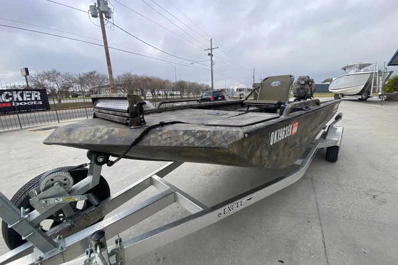 Slide: The Image of 2023 Excel F86 boat on trailer, camo design, parked outdoors. - 7
