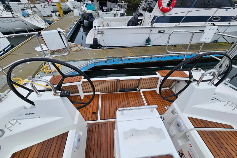 Slide: The Image of 2023 Beneteau Oceanis 34.1 yacht cockpit with dual steering wheels and wooden deck. - 6