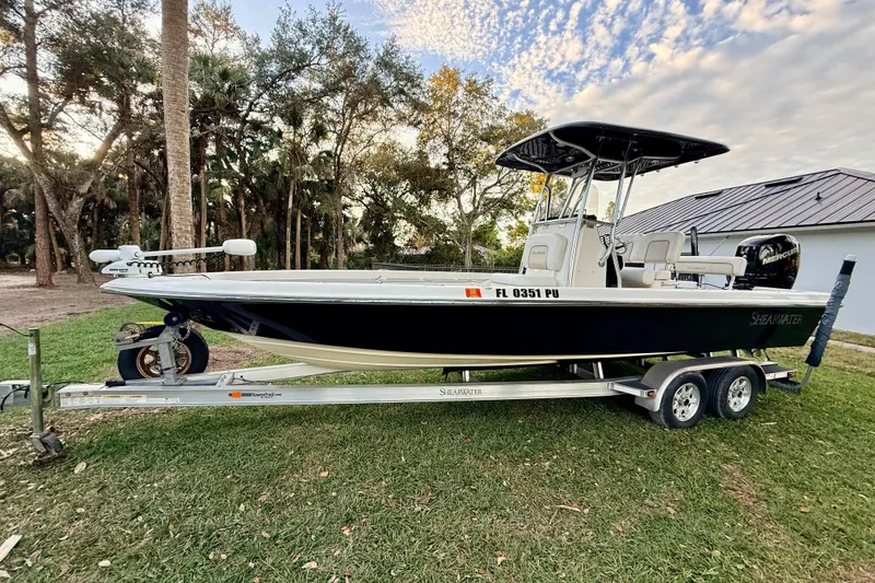 Slide: The Image of 2012 ShearWater 25LTZ boat on trailer, parked on grass with trees in background. - 10