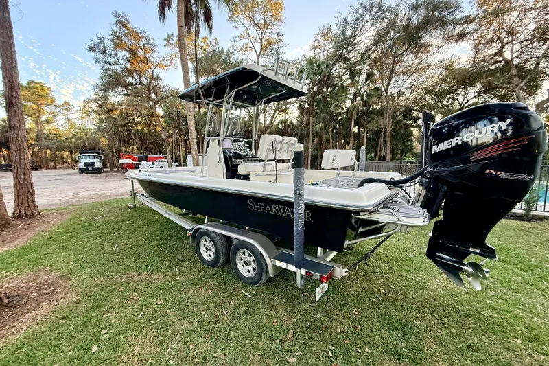 Slide: The Image of 2012 ShearWater 25LTZ boat on trailer with Mercury engine, parked on grass. - 11