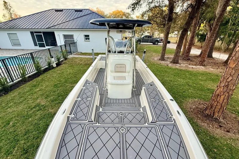 Slide: The Image of 2012 ShearWater 25LTZ boat with custom deck, parked near a house and trees. - 30
