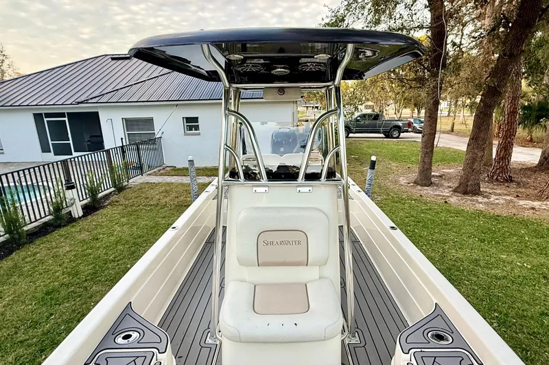Slide: The Image of 2012 ShearWater 25LTZ boat with center console, parked near a house and trees. - 34