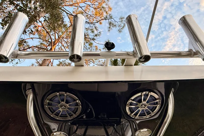 Slide: The Image of 2012 ShearWater 25LTZ boat with rod holders and speakers, set against a sky and tree backdrop. - 56