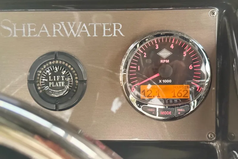 Slide: The Image of Dashboard of 2012 ShearWater 25LTZ boat showing RPM gauge and lift plate indicator. - 62