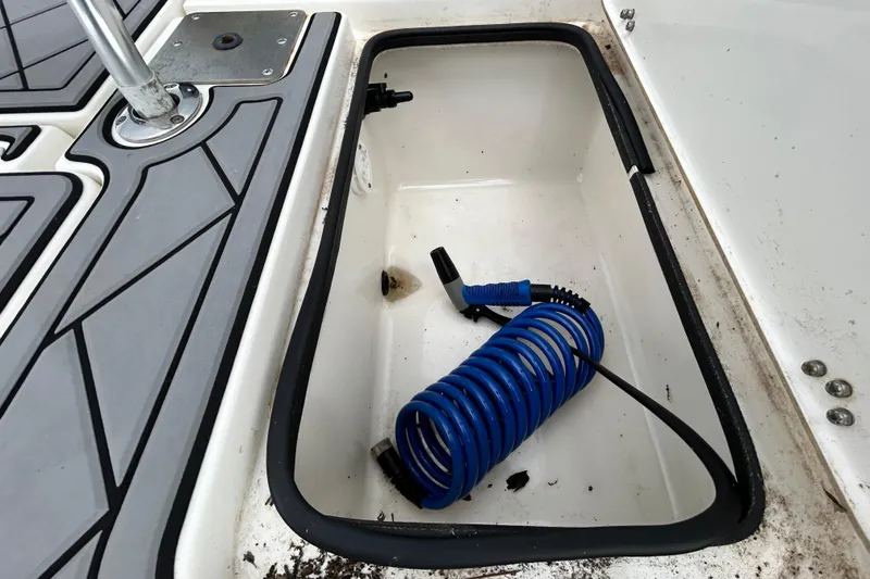 Slide: The Image of Storage compartment with coiled blue hose on 2012 ShearWater 25 LTZ boat. - 63