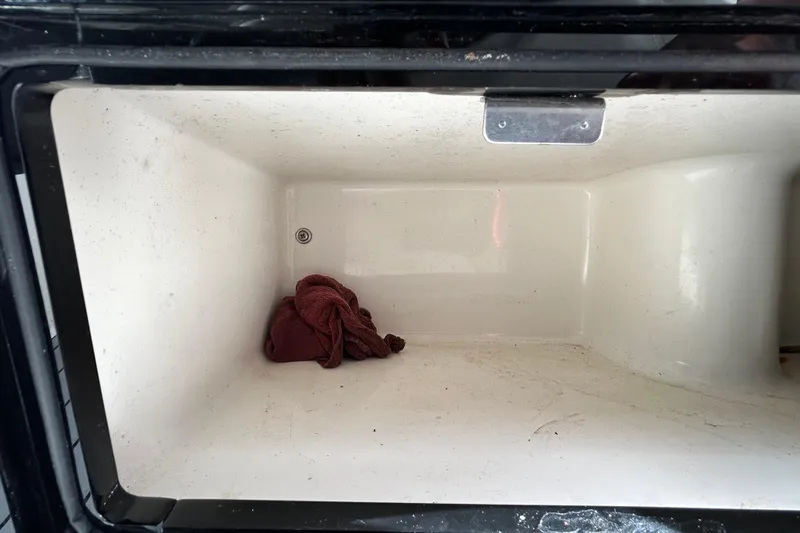 Slide: The Image of Empty storage compartment in a 2012 ShearWater 25 LTZ boat with a red cloth. - 68