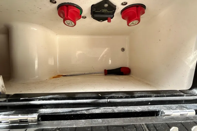 Slide: The Image of Storage compartment of 2012 ShearWater 25 LTZ boat with screwdriver and switches. - 69