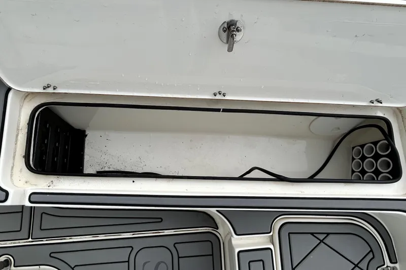 Slide: The Image of Open storage compartment on a 2012 ShearWater 25 LTZ boat, featuring rod holders. - 82
