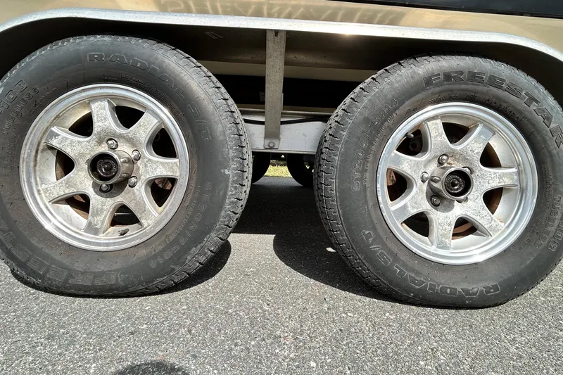 Slide: The Image of Trailer wheels of a 2012 ShearWater 25 LTZ boat on asphalt. - 87
