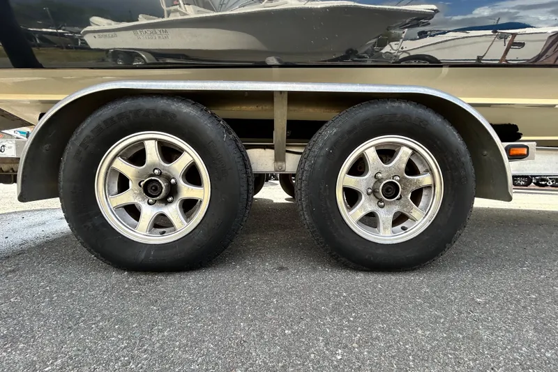 Slide: The Image of Trailer wheels of a 2012 ShearWater 25 LTZ boat on pavement. - 88