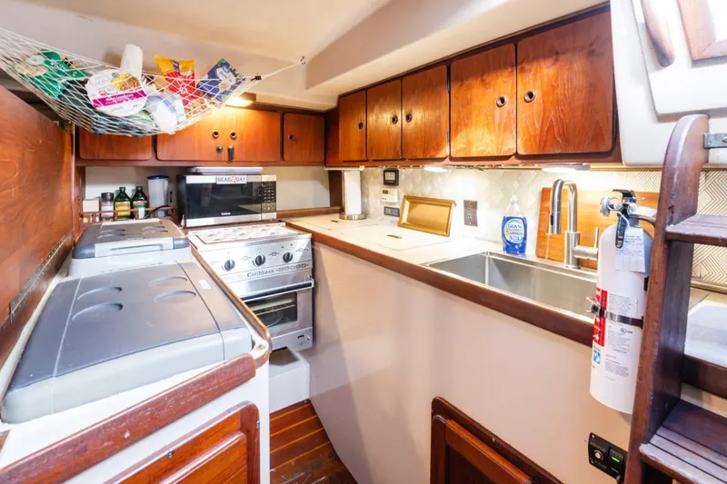 Slide: The Image of 1987 Morgan 41 Out Island Classic yacht kitchen with stove, sink, and wooden cabinets. - 24