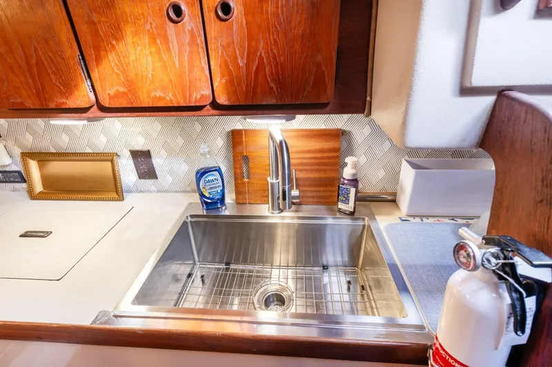 Slide: The Image of 1987 Morgan 41 Out Island Classic yacht kitchen with stainless steel sink and wooden cabinets. - 25