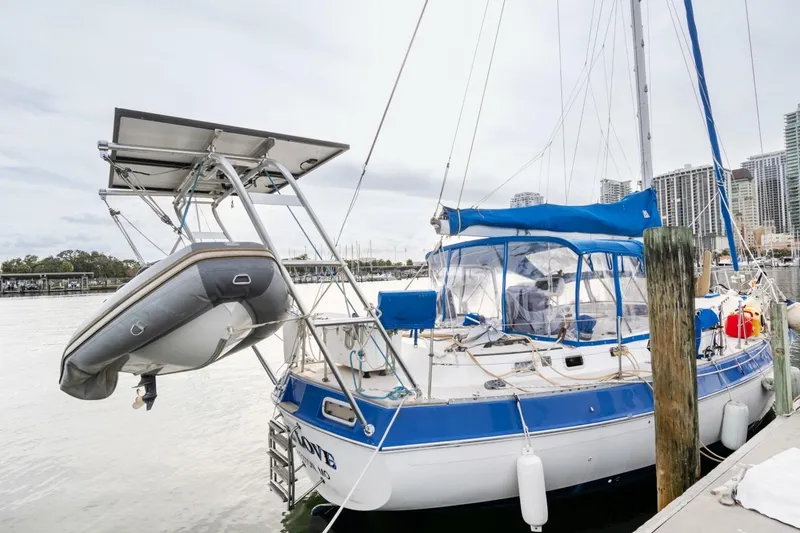 Slide: The Image of 1987 Morgan 41 Out Island Classic sailboat docked with dinghy and blue canopy. - 3
