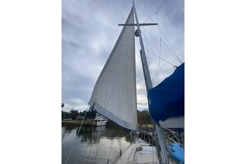 Slide: The Image of 1987 Morgan 41 Out Island Classic sailboat with raised sails on a calm waterway. - 44
