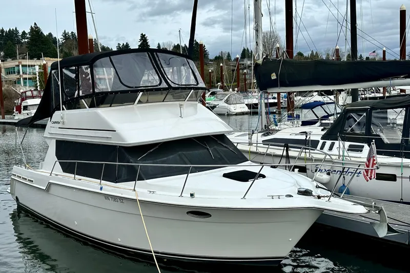 Slide: The Image of 1997 Carver 320 Voyager yacht docked in a marina, surrounded by other boats. - 13