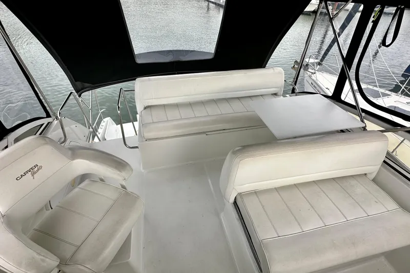 Slide: The Image of 1997 Carver 320 Voyager yacht interior with white seating and table, docked at marina. - 22