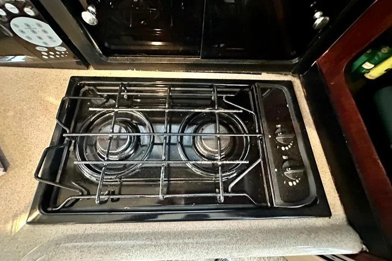 Slide: The Image of Stovetop in 1997 Carver 320 Voyager boat kitchen, featuring dual burners and control knobs. - 28