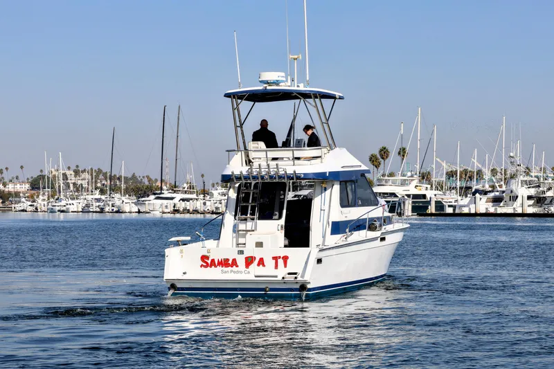Slide: The Image of 1988 Mediterranean 38 Convertible boat cruising in a marina with people onboard. - 2