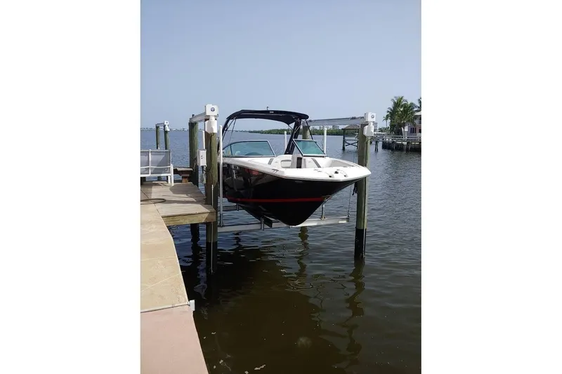 The Image of 2017 Regal 23 OBX boat on lift at dockside, calm water background. - 1