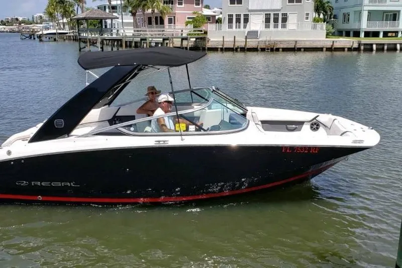 Slide: The Image of 2017 Regal 23 OBX boat cruising on a sunny waterfront with passengers. - 2