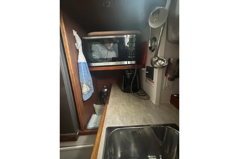 Slide: The Image of 1982 Campion 310 boat kitchen with microwave, sink, and hanging utensils. - 26