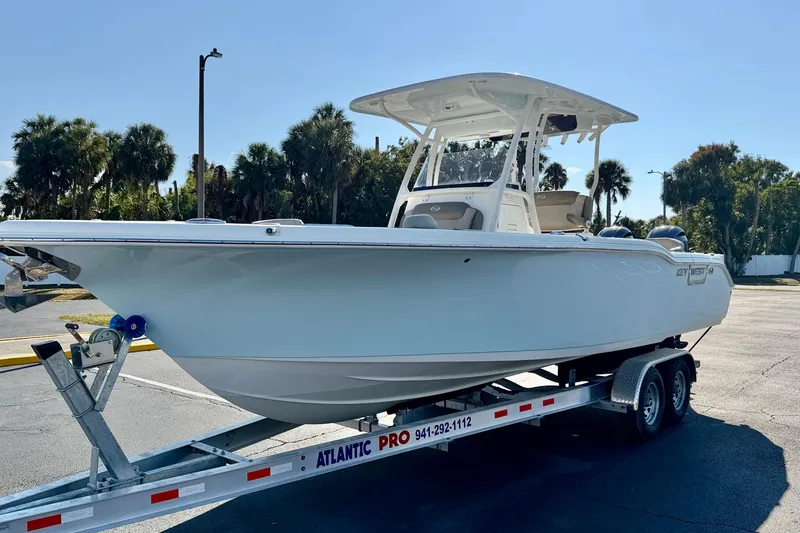 Slide: The Image of 2023 Key West 263 FS boat on trailer, parked outdoors with palm trees in background. - 2