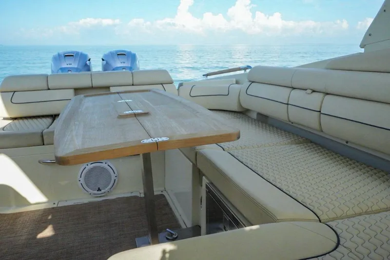 Slide: The Image of 2019 Chris-Craft Launch 35 GT OB interior with beige seating and wooden table on calm water. - 33