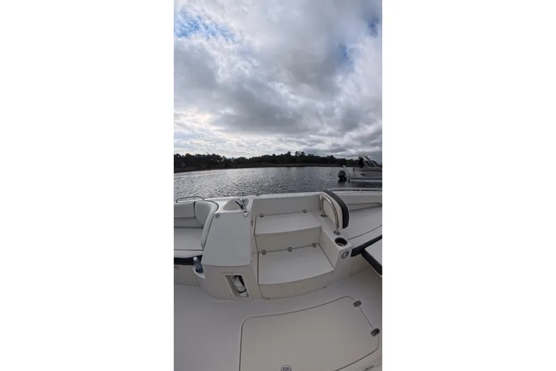 Slide: The Image of 2020 Stingray 212 SC boat interior with lake view under cloudy sky. - 10