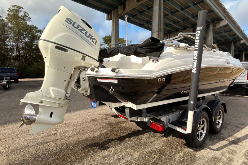 Slide: The Image of 2020 Stingray 212 SC boat with Suzuki engine on calm water. - 2