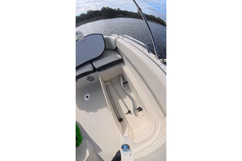 Slide: The Image of 2020 Stingray 212 SC boat interior with open storage compartment on a calm lake. - 7
