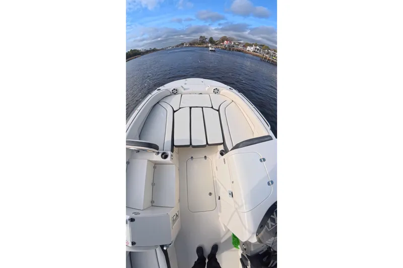 Slide: The Image of 2020 Stingray 212 SC boat interior with seating, on a calm waterway under a blue sky. - 9