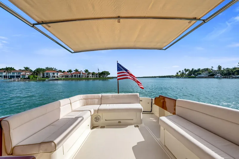 Slide: The Image of Hinckley Talaria 43 Motoryacht 2015, spacious deck with seating, American flag, scenic waterfront view. - 14