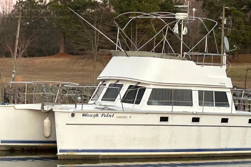 The Image of 2004 PDQ 34 Power Catamaran docked by a wooded shoreline. - 0