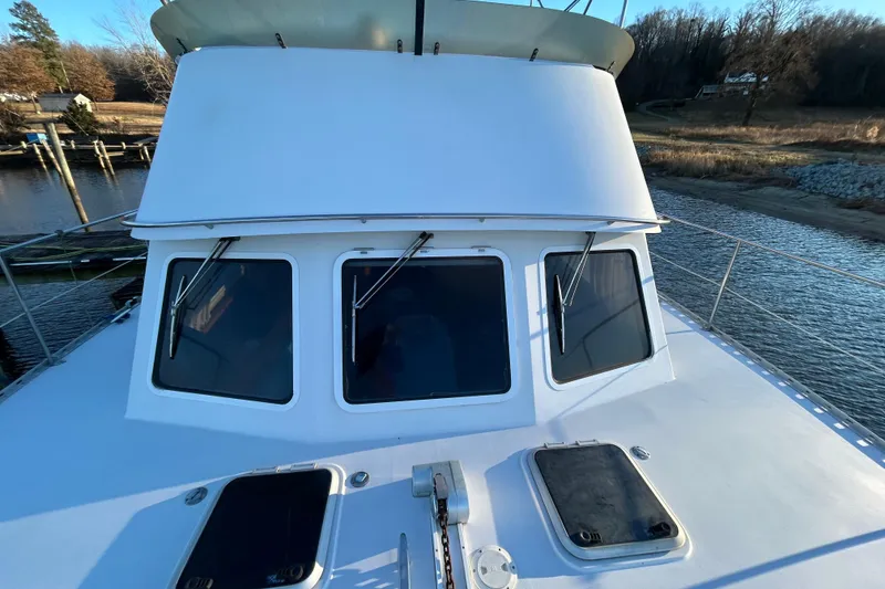 Slide: The Image of 2004 PDQ 34 Power Catamaran on calm water, showcasing front windows and deck hatches. - 10