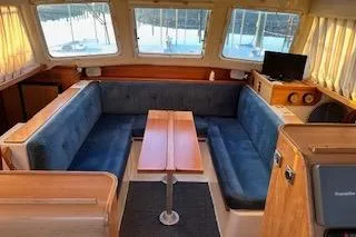 Slide: The Image of 2004 PDQ 34 Power Catamaran interior with blue seating, wooden table, and large windows. - 11