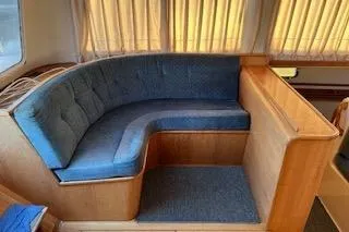 Slide: The Image of 2004 PDQ 34 Power Catamaran interior with blue cushioned seating and wooden accents. - 12